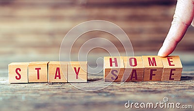 Announcement with wooden blocks to people, to stay at home to keep social distance. Stock Photo