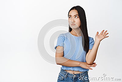 Annoyed arrogant asian woman roll eyes, looking away and wave hand to decline smth bothering her, standing over white Stock Photo