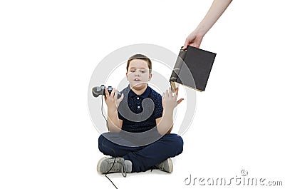 Annoyed boy. Little boy play video games mother`s hand puts him a book for learning Stock Photo