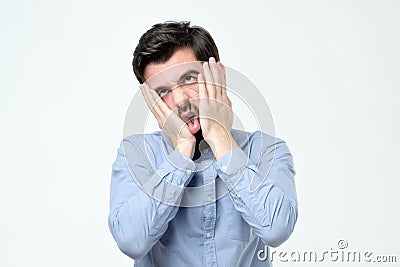 Annoyed guy with bristle, leaning face on hand and looking indifferent at camera Stock Photo