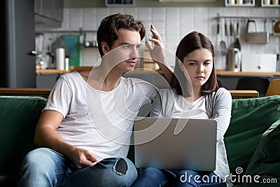 Annoyed husband reproaching frustrated wife wasting money on onl Stock Photo