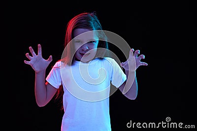 Annoyed little girl, kid in white t-shirt expressing neagtive emotions isolated over dark background. Concept of facial Stock Photo
