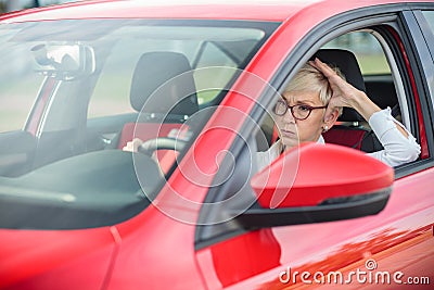 Annoyed mature woman sitting in a car, stuck in a traffic jam Stock Photo
