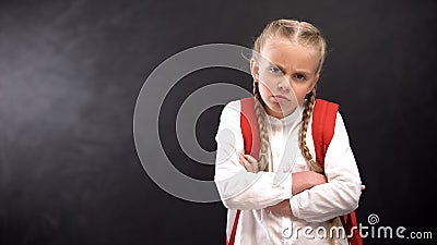 Annoyed schoolgirl with crossed hands looking at camera, education problems Stock Photo