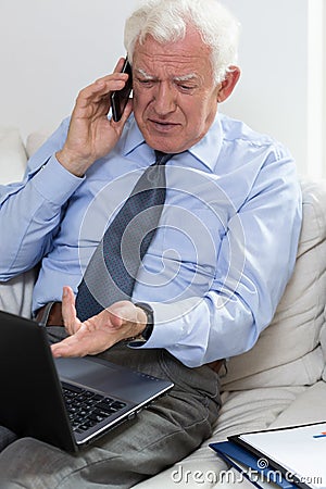 Annoyed senior businessman using laptop Stock Photo