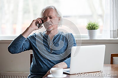 Annoyed aged man having unpleasant phone talk Stock Photo