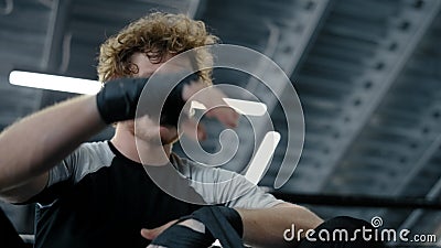Annoyed sportsman using boxing tape in sport club. Fighter wrapping hands at gym Stock Photo