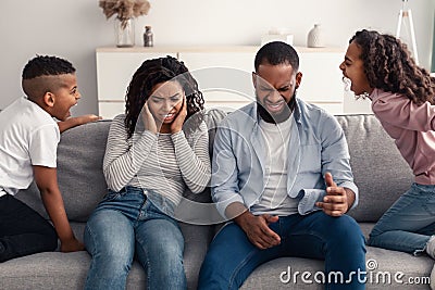 Angry black children fighting over their shocked parents Stock Photo