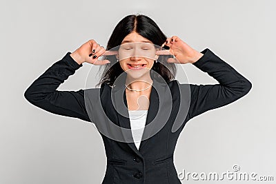 Annoyed young dark-haired girl in black blazer shut ears with fingers and grimacing from annoying loud noise, noisy neighbours or Stock Photo