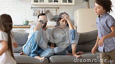 Tired young parents exhausted from loud kids playing Stock Photo