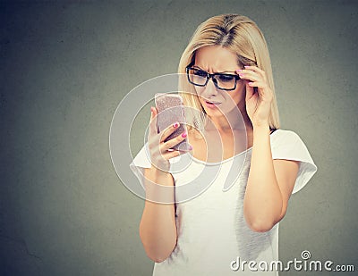 Annoyed upset woman in glasses looking at her cell phone with frustration Stock Photo