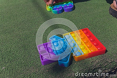 Anonymous child hold in his hands sensory toy pop it and shows it in front of himself.Rainbow color.Antistress toy for Stock Photo