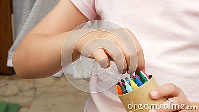 Anonymous child, school age girl holding a box of crayons choosing one crayon detail hands closeup, creativity arts and crafts art Stock Photo