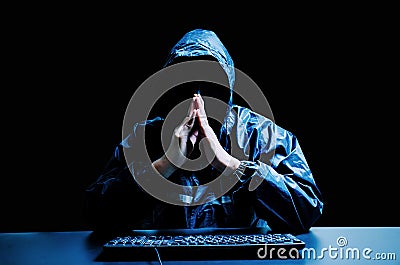 Anonymous computer hacker in white mask and hoodie. Obscured dark face with keyboard computer in the dark. Stock Photo