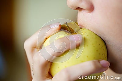 Anonymous girl eating delicious yellow apple at home Stock Photo