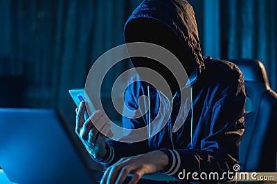 Anonymous hacker programmer uses a laptop to hack the system in the dark. Concept of cybercrime and hacking database Stock Photo