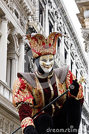 Anonymous man masked as a court jester for the Venice carnival. Historic building on the background. Editorial Stock Photo
