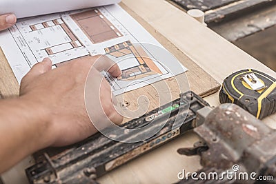 An anonymous man reviews the working drawings of a computer desk to be built at a furniture workshop Stock Photo