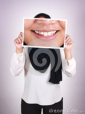 Anonymous muslim woman wearing hijab covering her face with big smile picture, happy white teeth Stock Photo