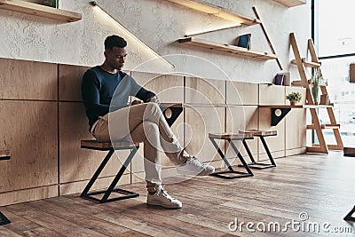 Another business message. Handsome young man using his smart phone while sitting in the creative working space Stock Photo