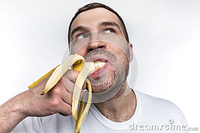 Another strange picture of unshaved guy eating ripe banana. He is biting a big piece of fruit. Man is enjoying the Stock Photo