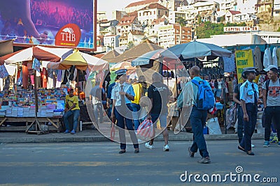 A police woman manages trafiic in a big city. Huge market in the background, crowd of people cross the street of Antananarivo Editorial Stock Photo