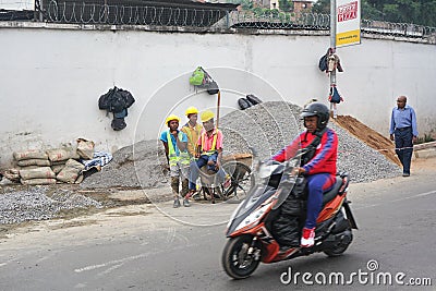 Antananarivo, Madagascar - April 24, 2019: Unknown Malagasy workers in hard hats and reflective jackets standing near gravel heap Editorial Stock Photo