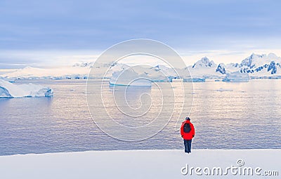 Antarctic tourist in red parka in front of Antarctic iceberg landscape at Portal Point Stock Photo