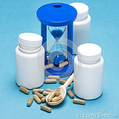 Anti-aging supplements and hourglass with pouring sand Stock Photo
