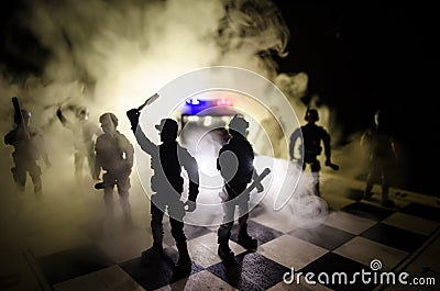 Anti-riot police give signal to be ready. Government power concept. Police on chessboard. Smoke on a dark background with lights. Stock Photo