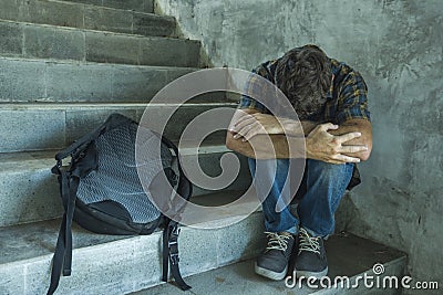Campaign vs homophobia with young sad and depressed college student man sitting on staircase desperate victim of harassment Stock Photo