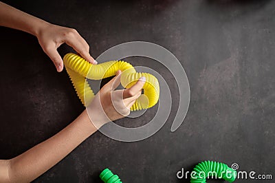 anti stress sensory pop tube toys in a children`s hands. a little happy kids plays with a poptube toy on a black table. toddlers Stock Photo