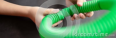 Anti stress sensory pop tube toys in a children`s hands. a little happy kids plays with a poptube toy on a black table. toddlers Stock Photo