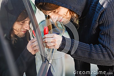 Thieft man holding screwdriver breaking into car Stock Photo