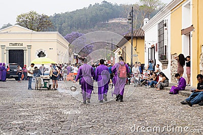 Three purple robbed men with incense smoker on the cobbled streets for the procession San Bartolome de Becerra, Antigua, Guatemala Editorial Stock Photo