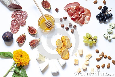 Antipasti food white flat lay with nuts, honey, cured meat, salami, cheeses, grapes and figs. Stock Photo