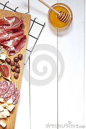Antipasti food white flat lay with nuts, honey, cured meat, salami, cheeses, grapes and figs. Stock Photo