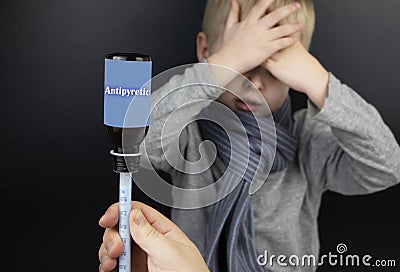 Antipyretic drug for a child. Medicinal syrup in a syringe on the background of a sick boy. The concept of treating children at Stock Photo