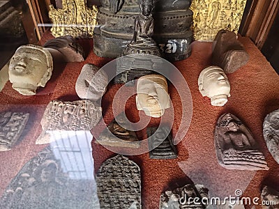 Antique and ancient holy amulets and Buddha heads collection behind window Editorial Stock Photo