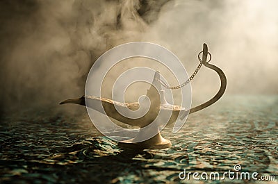 Antique arabian nights style oil lamp with soft light white smoke, Dark background. Lamp of wishes concept. Toned Stock Photo