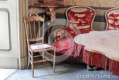 Antique armchairs in pure gold and torn red silk Stock Photo