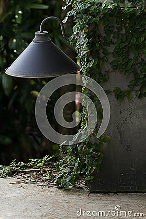 Black bollard light in green fresh leaves of tree Stock Photo