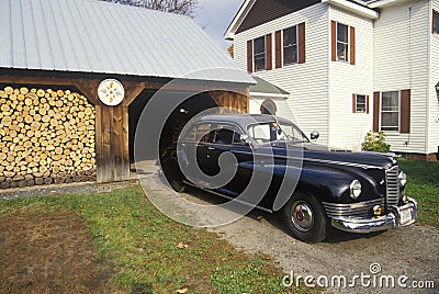 An antique car and stack of firewood in New England Editorial Stock Photo