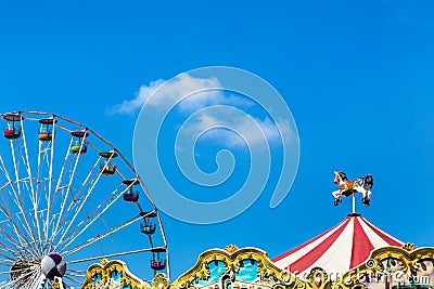 Antique carousel horses tent in amusement park with colourful ferris wheel Editorial Stock Photo