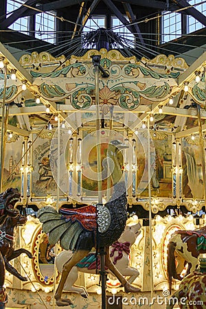 An antique carousel with an inticate ostrich carving below and mechanical systems visible overhead Editorial Stock Photo