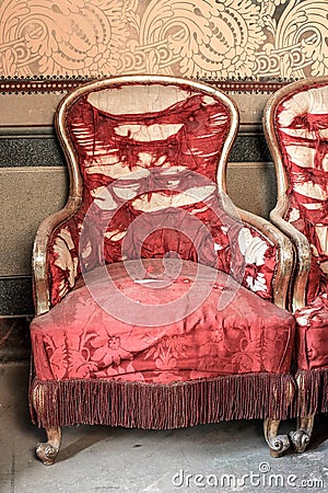 Antique armchairs in pure gold and torn red silk Stock Photo