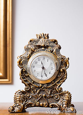 Antique clock in golden colors decorated with ornaments Stock Photo