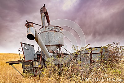 Antique combine rusting in a farmers field with bullet holes in it Stock Photo