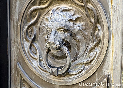 Antique decorative handle knocker on wooden vintage house door. Classical metal bronze lion head Stock Photo