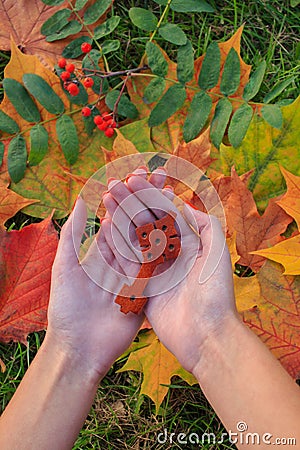 The antique Ethiopian Orthodox traditional cross in the woman's palms. Autumn leaves on background Stock Photo